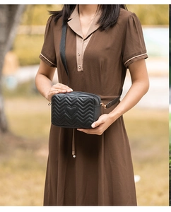 Detail of chevron quilted camera bag with heart embroidery and golden hardware