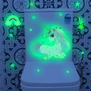 Glow-in-the-dark unicorn and stars wall decal set shown on a white toilet in darkness