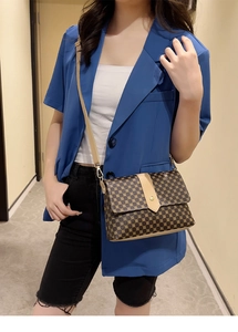 Detalle de bandolera vintage con estampado de puntos, solapa y hebilla de metal