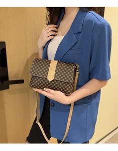 Vista puesta de un bolso vintage con monograma combinado con una chaqueta azul