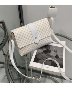 Primer plano de un bolso bandolera de cuero blanco con estampado geométrico amarillo