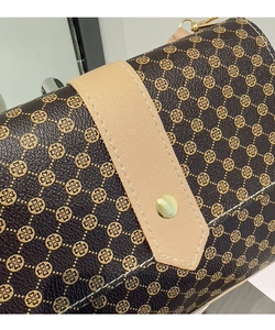 Detalle del bolso con estampado floral vintage, hebilla dorada y textura de costura