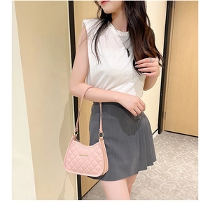 Detailed view of pink quilted handbag with gold logo and elegant stitching texture