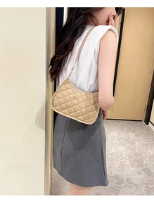 Detail of elegant beige quilted hobo bag featuring fine stitching and gold logo plaque