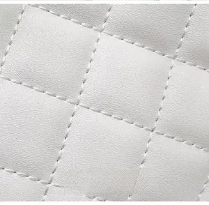 Close-up of white quilted leather texture with detailed diamond embroidery stitching