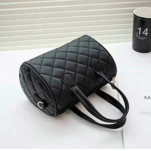 Detail of classic black quilted pattern on Boston handbag with gold metal hardware