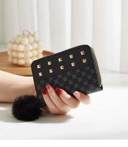 Détail du porte-monnaie à pois noirs avec clous dorés et breloque pompon en peluche
