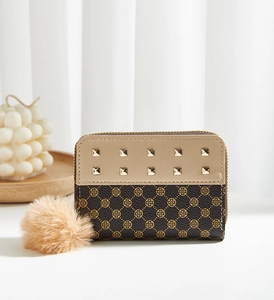 Détail d'un petit portefeuille zippé avec clous, imprimé fleuri et pompon en fourrure