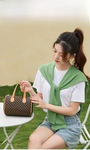 Detail of vintage barrel bag featuring brown floral pattern and leather handles
