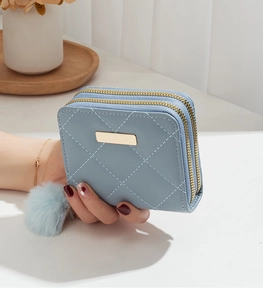 Détail du portefeuille matelassé bleu clair avec double fermeture et pompon décoratif