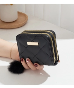 Détail du portefeuille matelassé noir à double zip avec plaque dorée et pompon