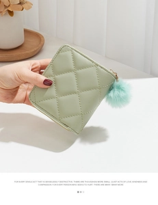 Gros plan d'un portefeuille matelassé vert menthe avec pompon en fausse fourrure