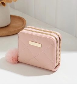 Gros plan du porte-monnaie matelassé rose à double couche avec décor doré et pompon en peluche