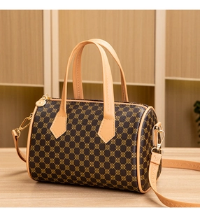 Detail view of brown boston bag featuring golden ring prints and metallic hardware