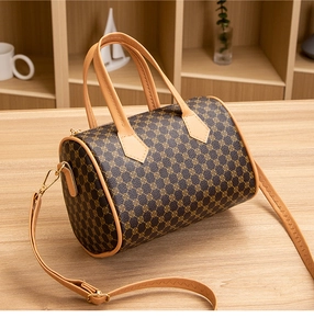 Detail of Boston-style cylinder bag showing brown floral print and golden metal hardware