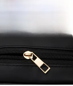 Detailed macro view of the gold metal zipper on black litchi textured leather bag