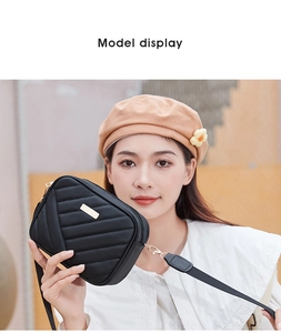 Close-up of black quilted camera bag with adjustable shoulder strap and metal plate detail