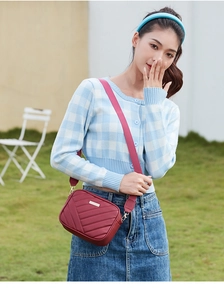 Close-up of red quilted nylon crossbody bag with V-pattern stitching and metal logo detail
