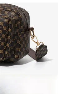 Detail of dark brown lychee leather cross-body bag with golden floral pattern and hardware