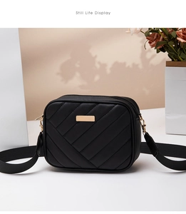 Detail view of black quilted crossbody bag with gold hardware and wide adjustable strap
