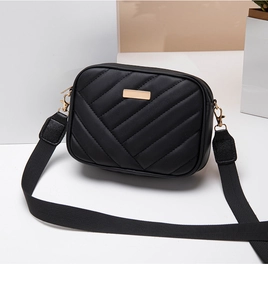 Close-up of black quilted camera bag with V-shaped stitching and gold metallic hardware