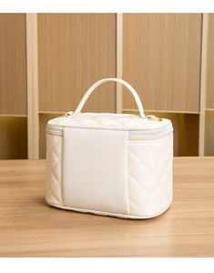 Gros plan sur la trousse à maquillage matelassée crème avec détails en métal doré