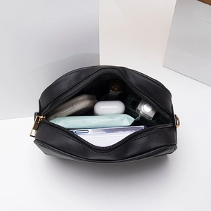 Quilted black crossbody camera bag for women with gold zipper showing interior storage