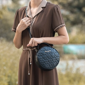 Chic black round crossbody bag with heart quilted texture and gold logo detail