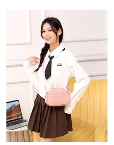 Close-up of pink quilted crossbody bag with gold logo and wide fabric shoulder strap