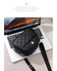 Detail of black quilted shoulder bag featuring flower metal clasp and woven strap
