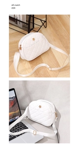 Detail of white quilted shell bag with golden flower logo and adjustable strap texture
