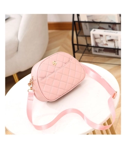 Pink quilted crossbody bag with gold flower clasp on a marble table setting