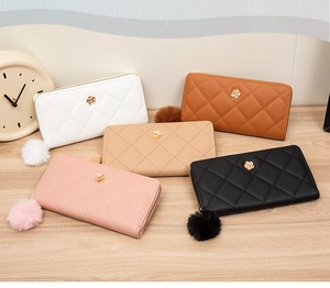 Group shot of long zipper wallets in five colors with quilted pattern and pompom charms