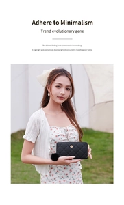 Long black quilted wallet with flower buckle and fur pompom on grass background