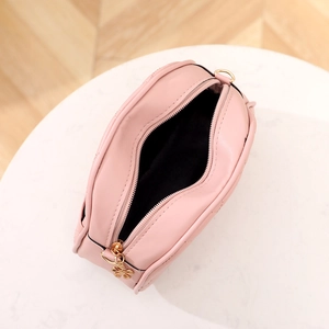 Pink quilted crossbody bag with floral zipper pull and gold hardware on white marble base