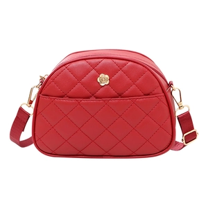 Red quilted shell crossbody bag with floral emblem and adjustable strap on white background