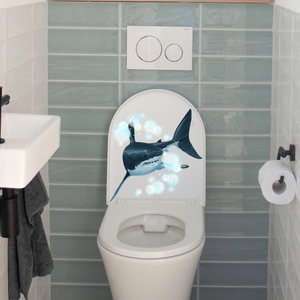 Luminous shark toilet lid sticker in a clean bathroom scene with blue sea bubbles