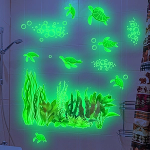 Glow in the dark sea turtle and seaweed wall decals in a dark bathroom setting