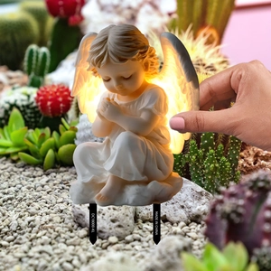 Detailed view of angel garden light with glowing wings set in outdoor greenery