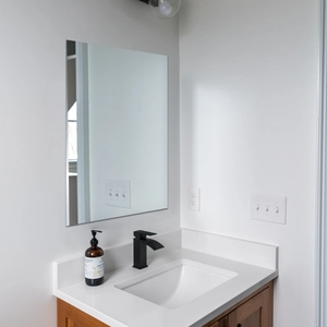 Close-up of frameless rectangular wall mirror with polished edges in modern bathroom