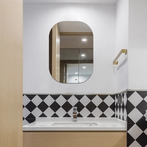 Frameless capsule-shaped bathroom mirror with rounded edges on a diamond tile wall