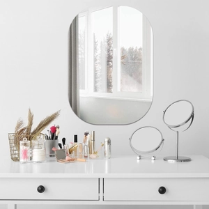 Modern capsule-shaped frameless wall mirror mounted above a white vanity desk