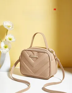 Detail of beige PU leather bag with V-shaped quilting and golden metal logo