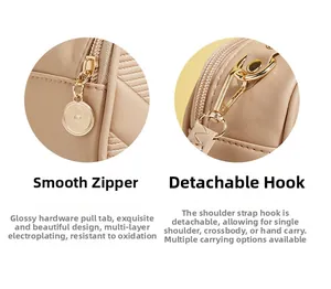 Detail of gold electroplated zipper and detachable metal hook on beige crossbody bag