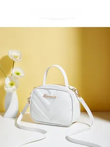 Detail view of white V-quilted faux leather handbag with gold logo and shoulder strap