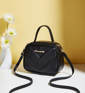 Close-up of black crossbody bag featuring V-shaped stitching and gold metal logo detail