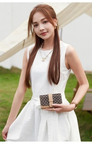 Short fold wallet in dark coffee monogram canvas with brown leather trim held by model