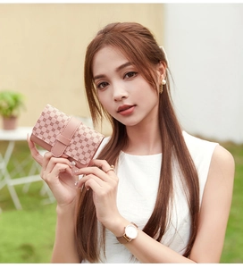 Pink floral leather wallet with snap closure shown held in hand against grassy backdrop
