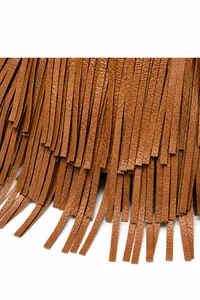 Macro shot of layered fringe detail and fine leather texture on caramel shoulder bag