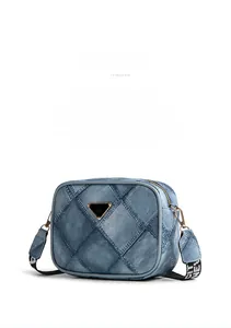 Detail of light blue denim camera bag with quilted pattern and wide woven strap